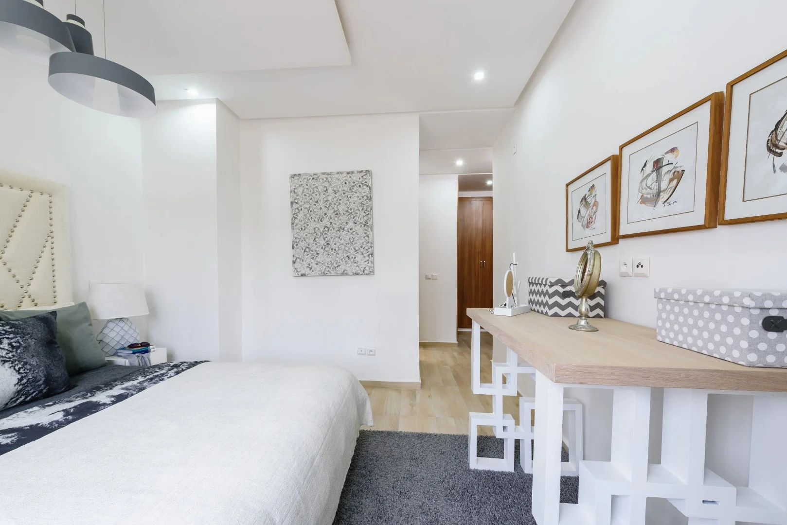 Chambre moderne avec lit double et espace bureau dans appartement lumineux