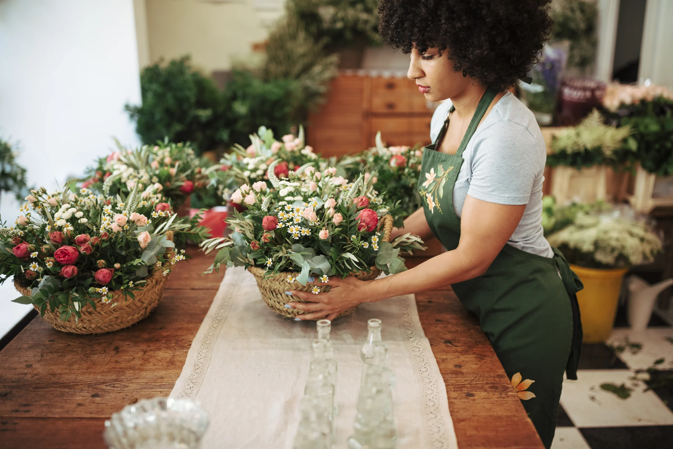 Fleuriste préparant un bouquet dans un panier avec différentes fleurs et plantes