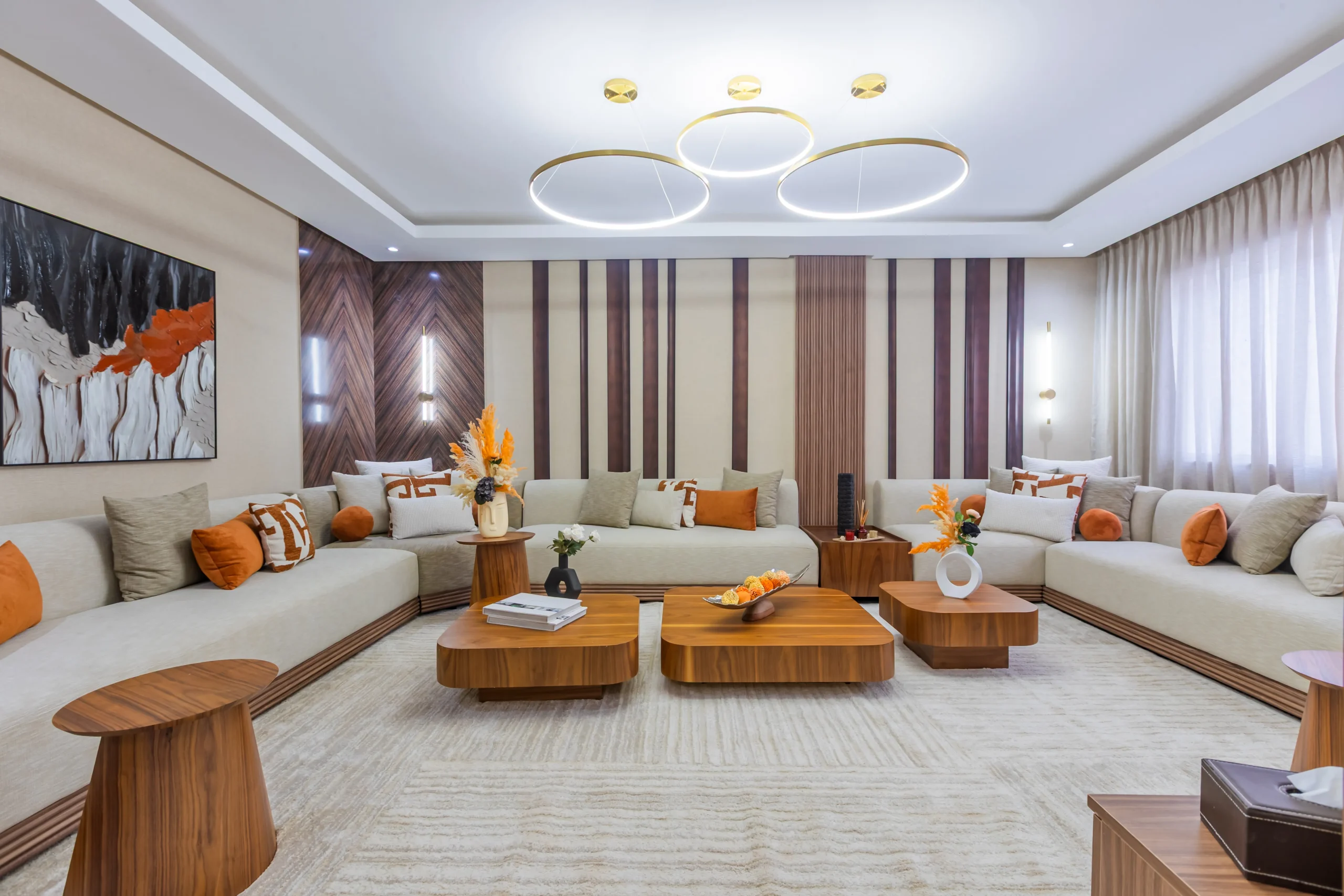 Grand salon contemporain avec canapé d’angle beige, tables en bois et décoration aux tons orange