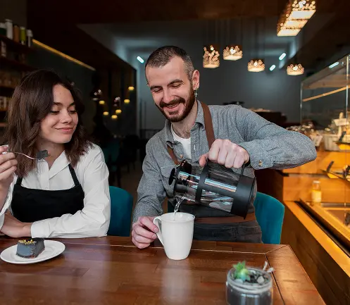 Serveur préparant un café pour des clients dans un café chaleureux