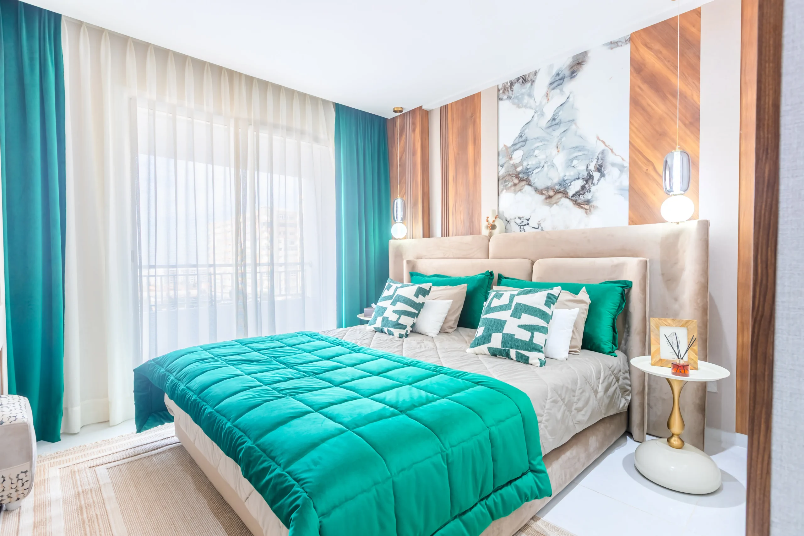 Chambre parentale moderne avec lit capitonné beige, couvre-lit vert émeraude et décoration épurée