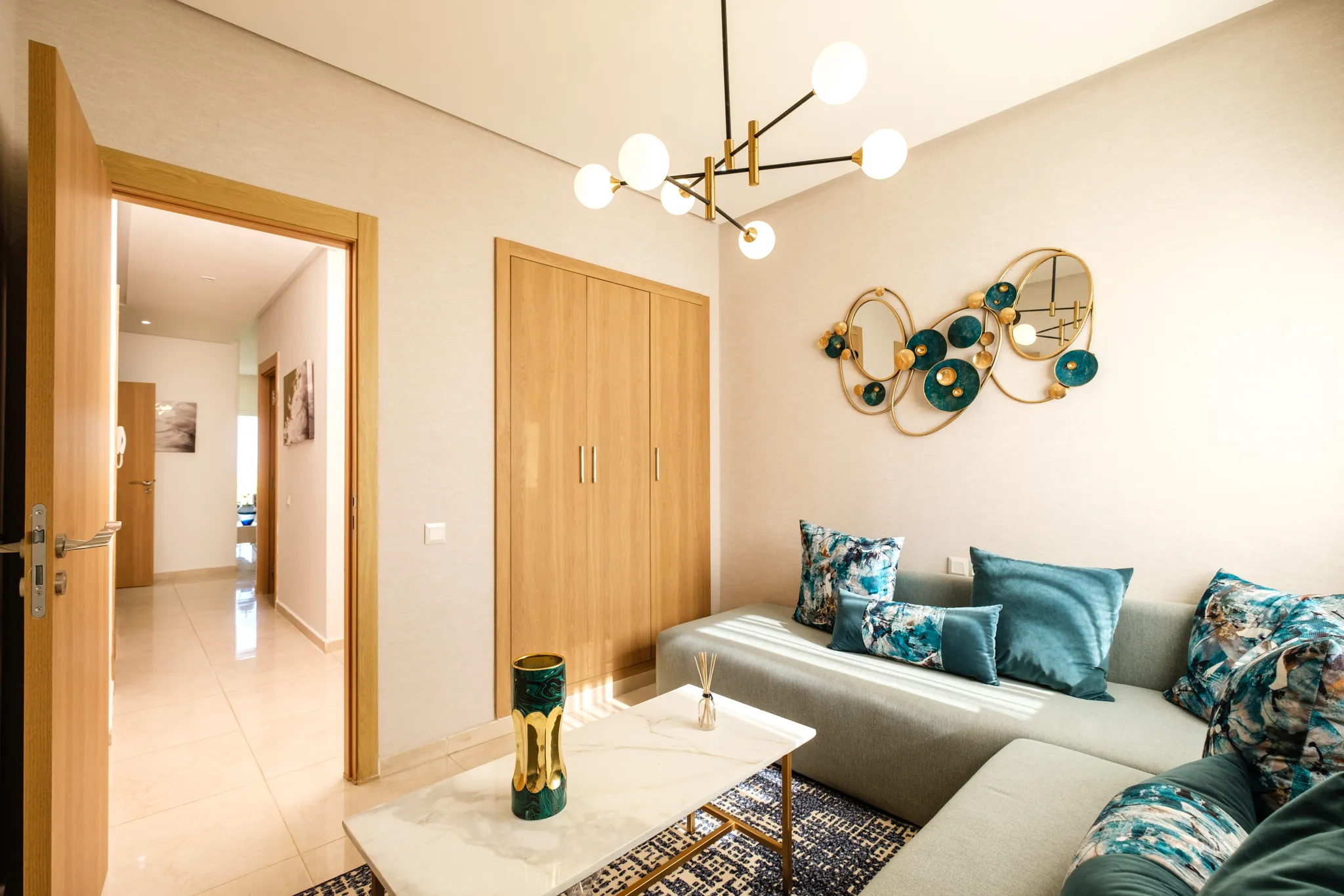 Coin salon avec canapé gris, placard en bois intégré et luminaire moderne en métal noir.