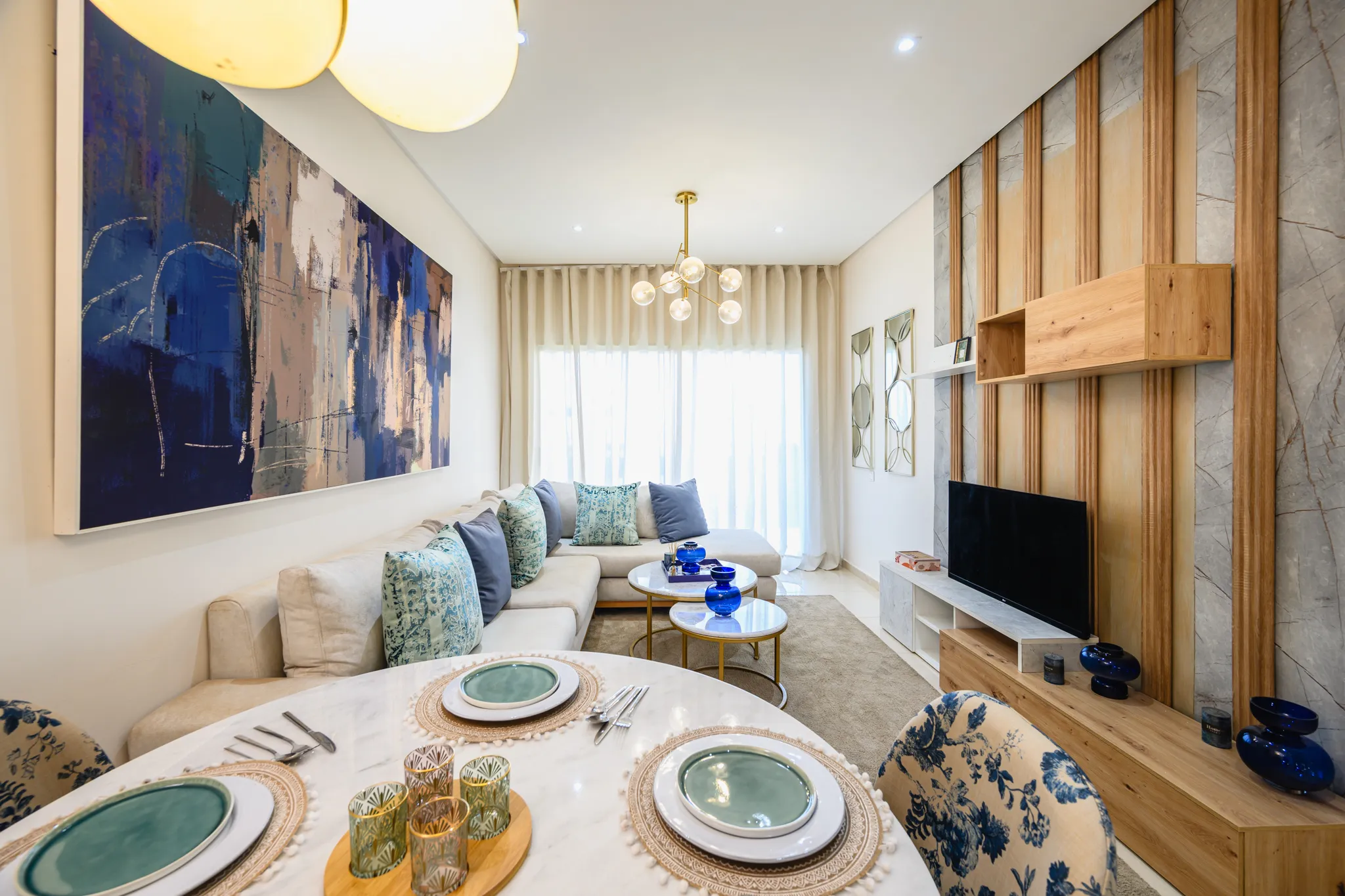 Grand séjour avec coin salle à manger, décoration artistique murale et mobilier moderne dans un appartement neuf.