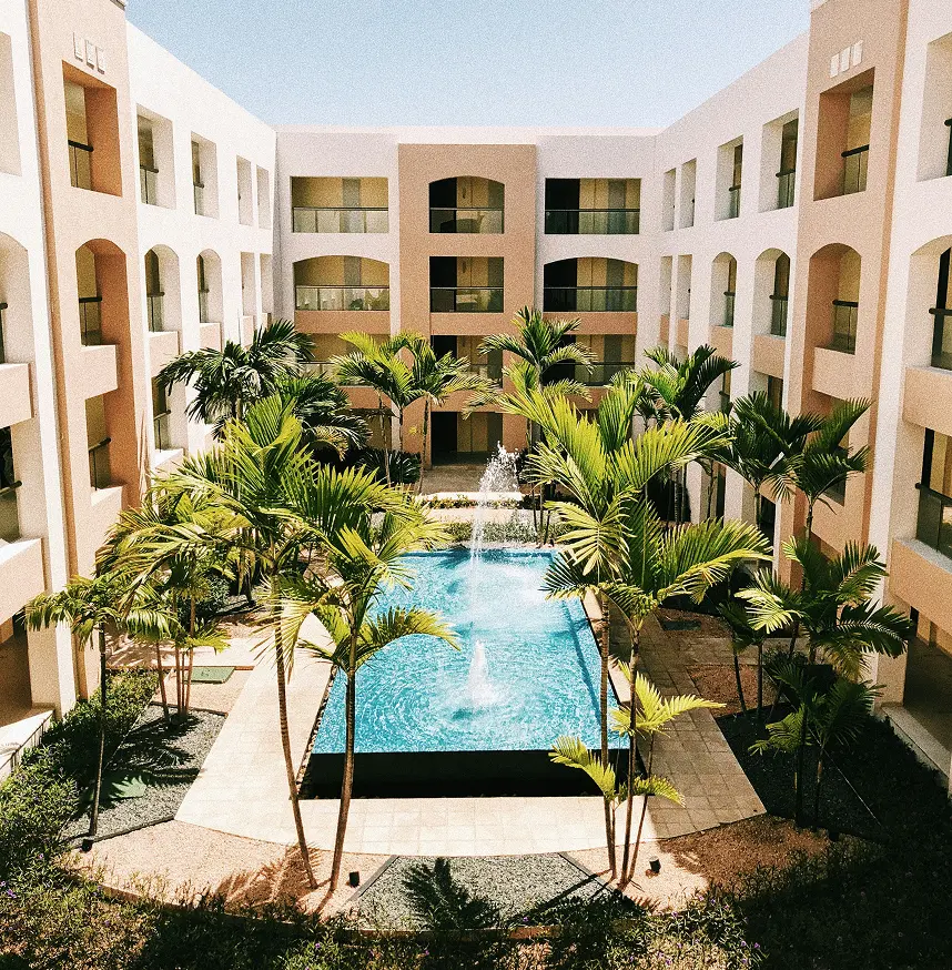 Résidence hôtelière moderne avec piscine centrale et jardin de palmiers en patio