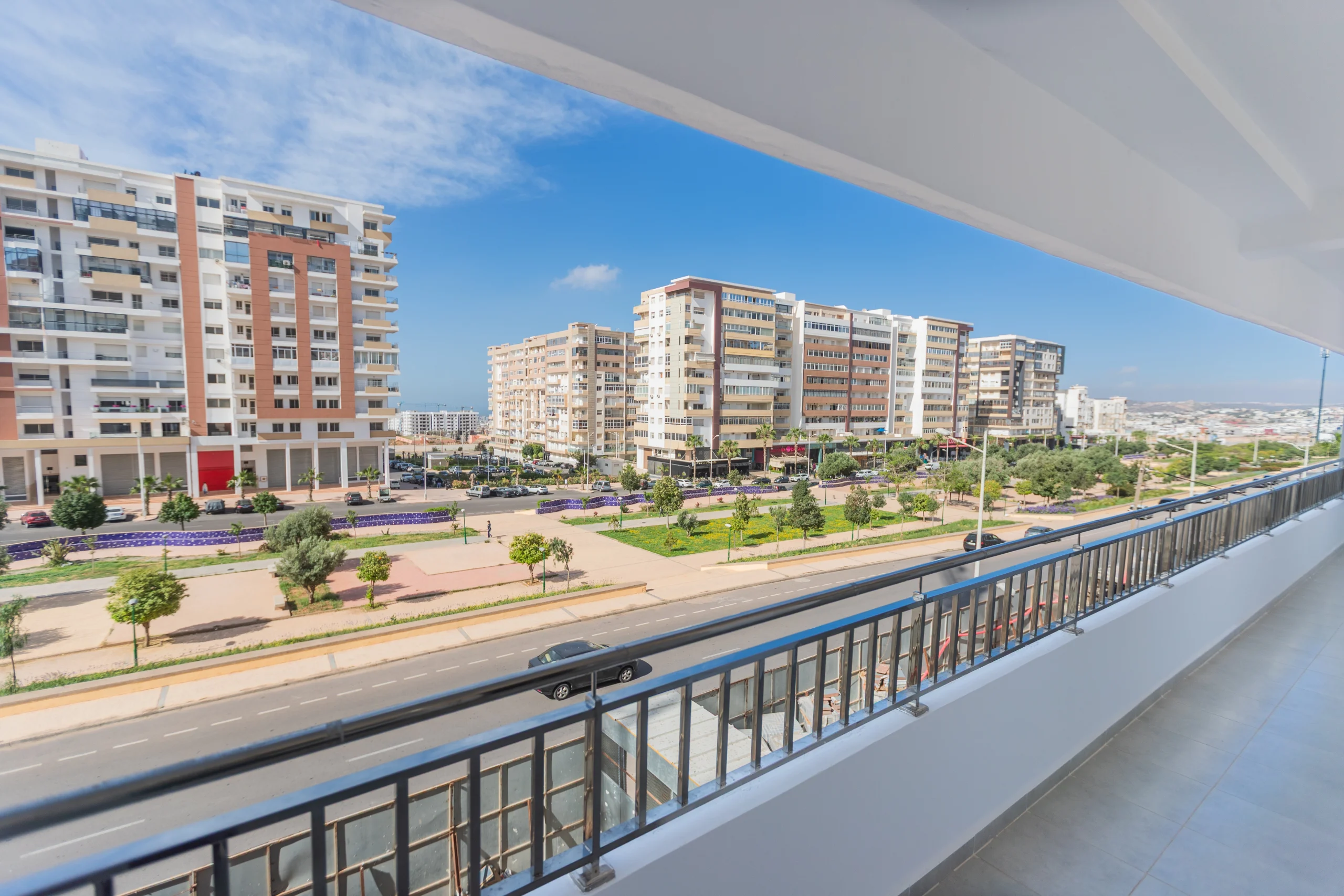 Vue panoramique depuis un balcon sur un large boulevard arboré et des immeubles modernes à Ville Agadir.
