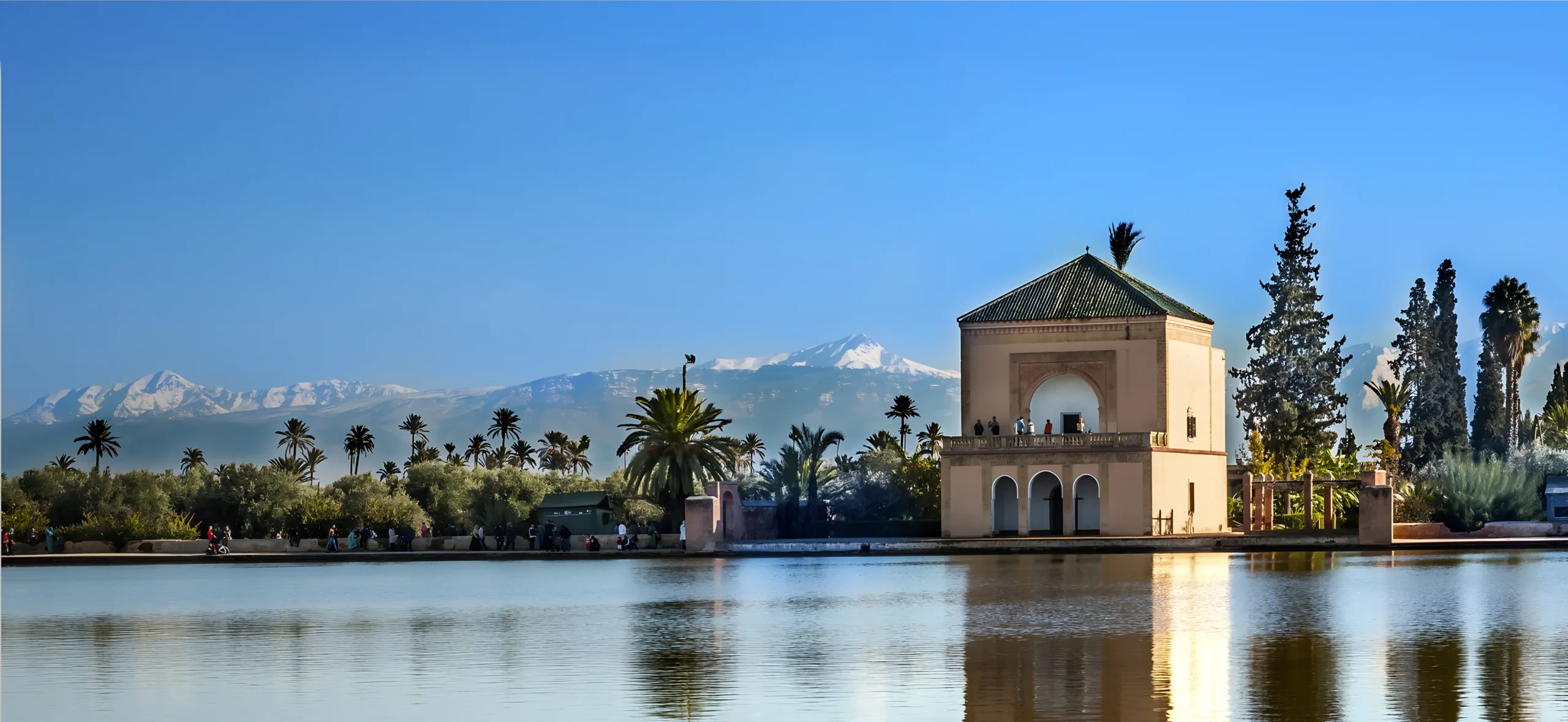 Vue du pavillon de la Ménara à Marrakech reflété dans le bassin avec les montagnes de l’Atlas enneigées en arrière-plan