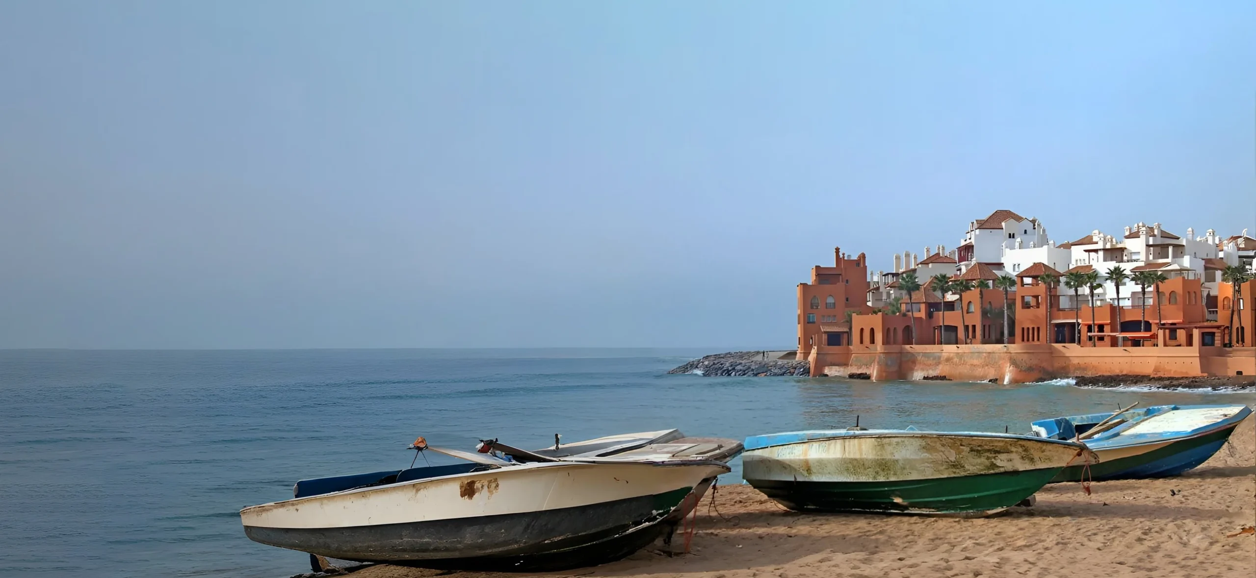 Barques de pêche sur la plage de Bouznika avec résidences en bord de mer au Maroc