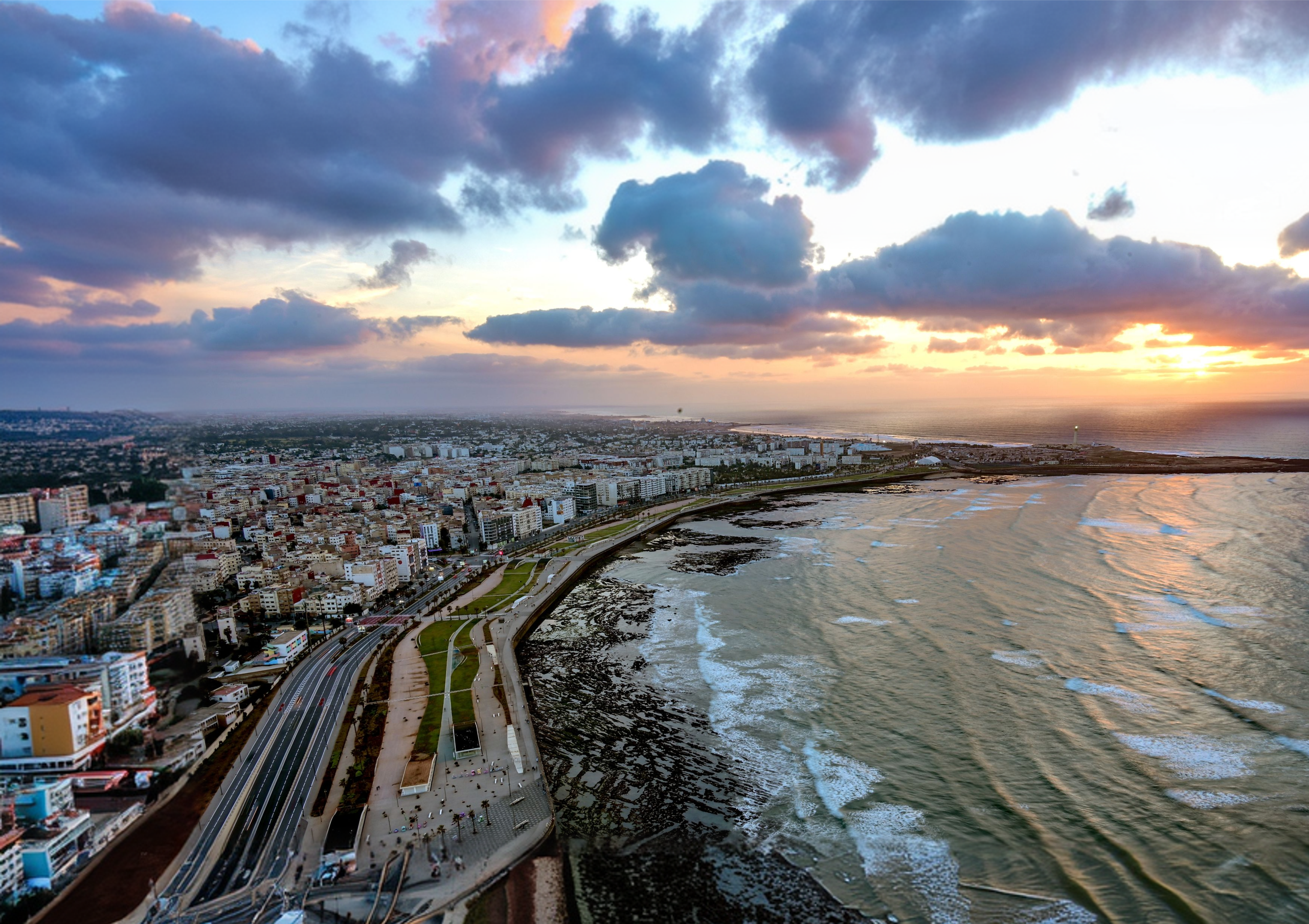 Vue panoramique de la Corniche de Casablanca et de l’océan Atlantique sous un ciel nuageux au coucher du soleil